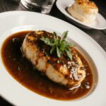 Smothered chicken breast served with rich brown gravy and fresh parsley garnish on a white plate