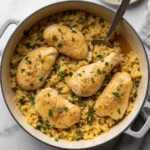 Smothered chicken drumsticks and thighs with yellow rice in a Dutch oven, garnished with parsley