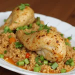 Braised chicken legs served over seasoned couscous, garnished with chopped green onions and fresh herbs.