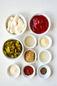 Classic burger sauce ingredients in small bowls including mayonnaise ketchup pickles mustard and spices